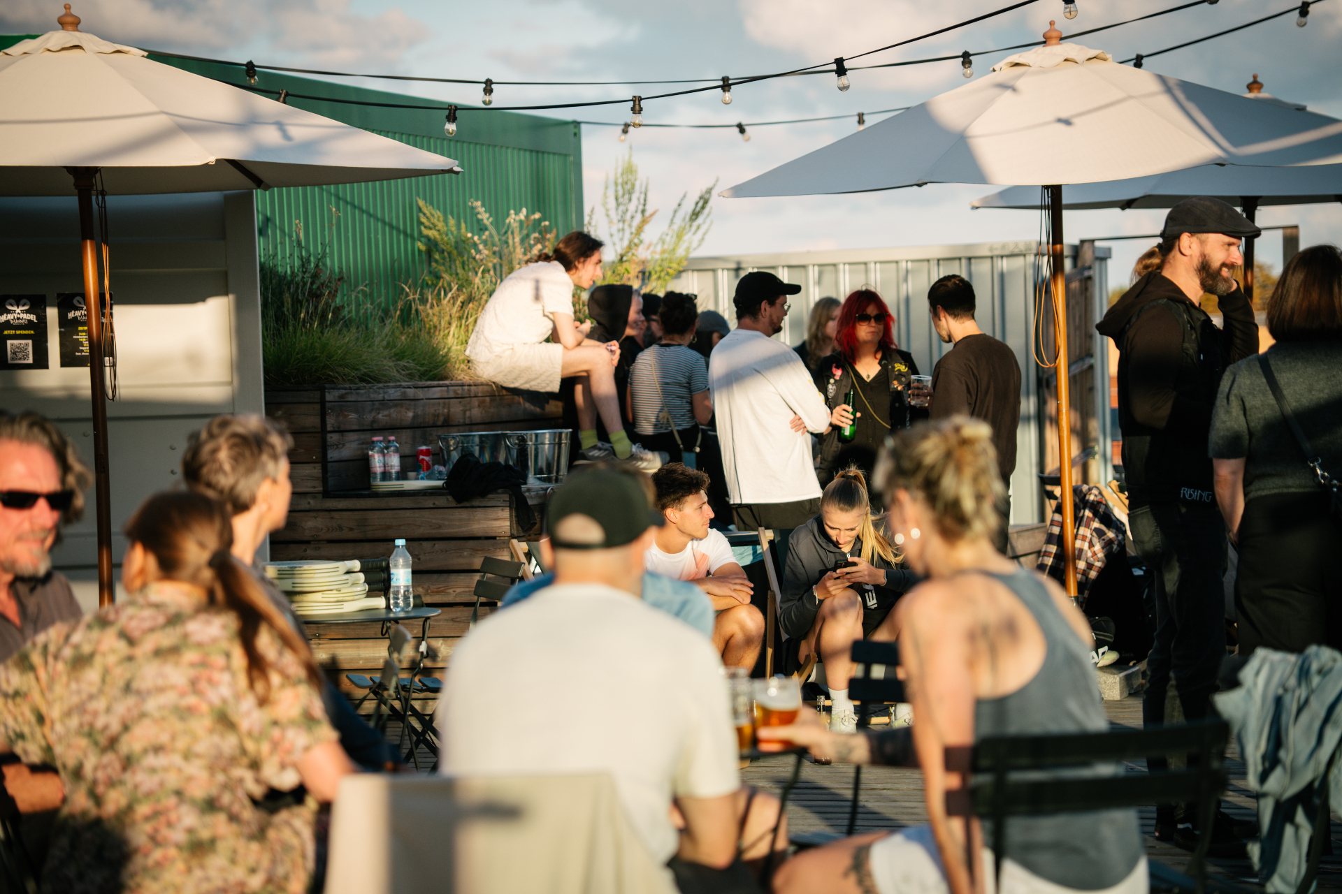 HEAVY PADEL TRUANTS guests on a sunlit Berlin rooftop terrace at golden hour